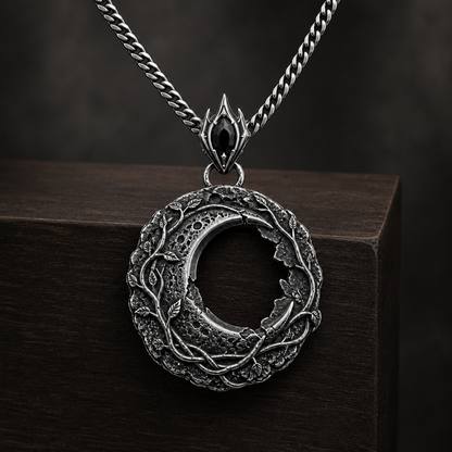 Oxidized 925 sterling silver hollow moon pendant with raised vine details, crater-like texture, ornate bail and included curb chain on a black background.