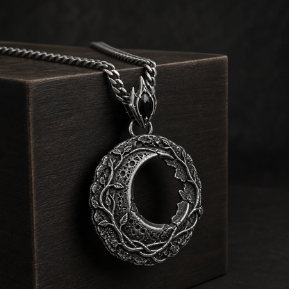 Oxidized 925 sterling silver hollow moon pendant with raised vine details, crater-like texture, ornate bail and included curb chain on a black background.