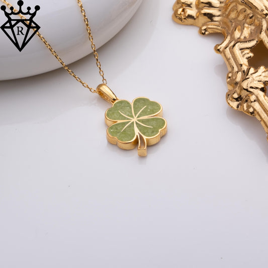 Green four-leaf clover necklace styled beside a white dish and gold-tone decorative object