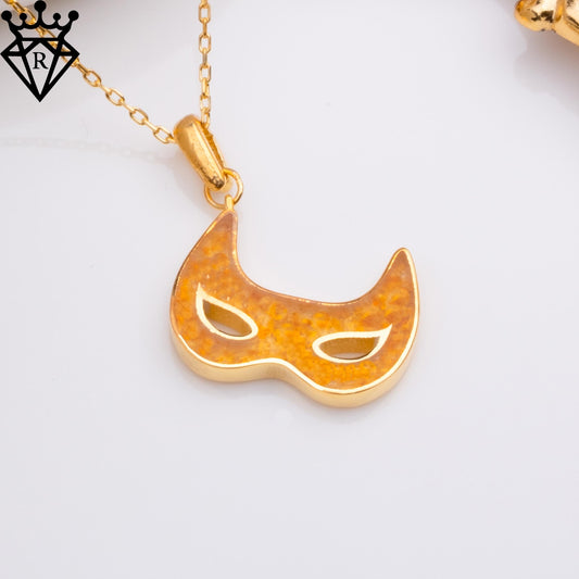 Close-up of the amber-toned Venetian mask pendant with two open eye-shaped cutouts and a black crown-and-diamond logo watermark