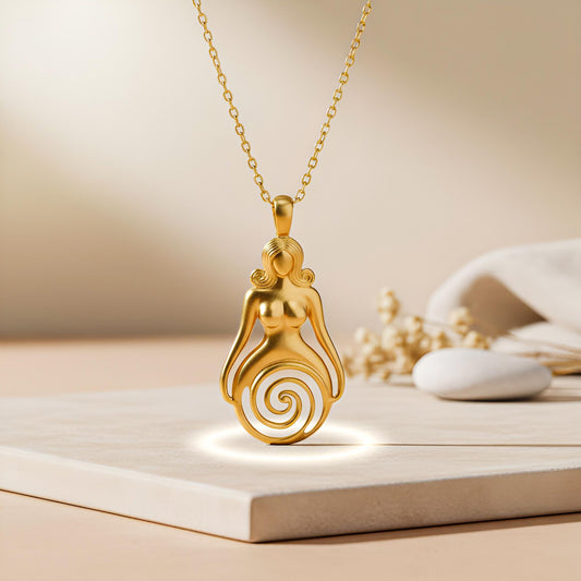 Gold Plated Silver Spiral Goddess Necklace displayed upright on a pale platform, showing the seated goddess-inspired figure and open lower spiral