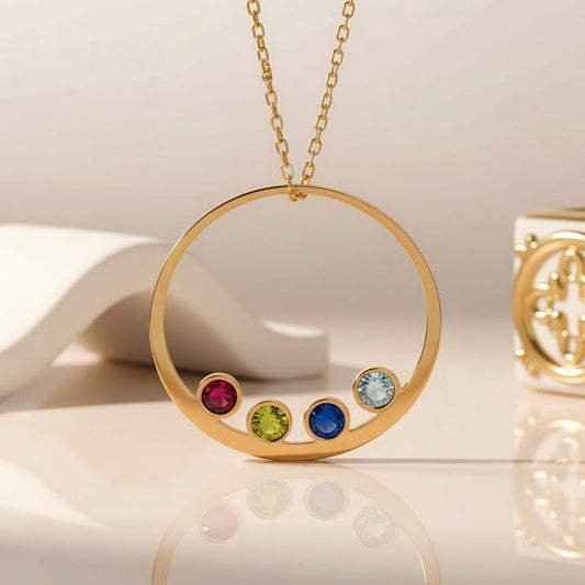 Gold Plated Silver open circular Family Birthstone Necklace with four colored stone settings on a neutral surface