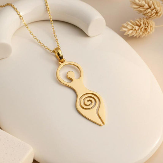 Close-up of a Gold Plated Silver Spiral Goddess pendant with curled upper detail and open lower spiral on a cream display