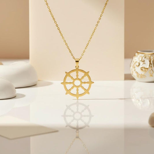 Gold Plated Silver Dharma Wheel pendant hanging above a reflective tabletop