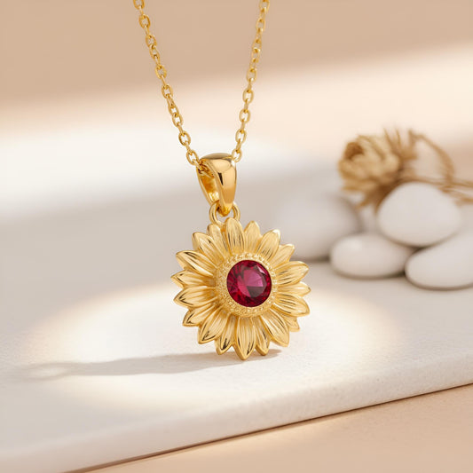 Close view of a Gold Plated Silver sunflower pendant with petal detailing and a round red center stone