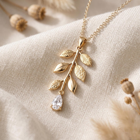 Gold Plated Silver Willow Drop Necklace with engraved leaves and a teardrop dangle on ivory fabric