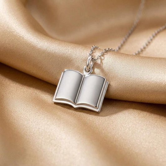 Close-up of the Open Book Necklace pendant on gold satin fabric