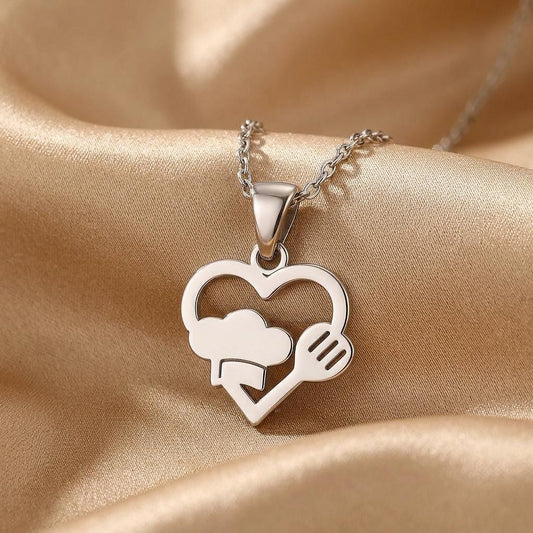 Close-up of the Love for Cooks heart pendant with chef hat and fork on champagne satin