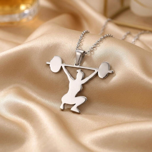 Close view of the polished kneeling athlete and overhead barbell pendant on satin fabric