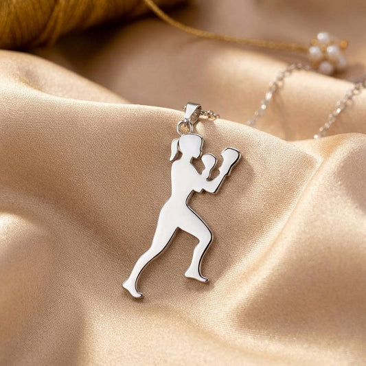 Close-up of the polished Boxer Woman pendant with raised gloves and a lunge stance on champagne satin