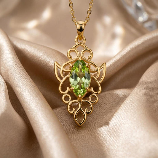 Elven Peridot Necklace close-up on champagne satin, showing the marquise-shaped green center stone and openwork frame