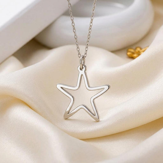 Outlined five-point pendant necklace displayed on cream satin beside a jewelry box