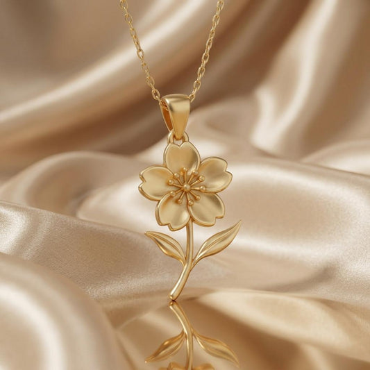 Close-up of the Gold Plated Silver five-petal cherry blossom pendant with curved stem and two leaves on satin
