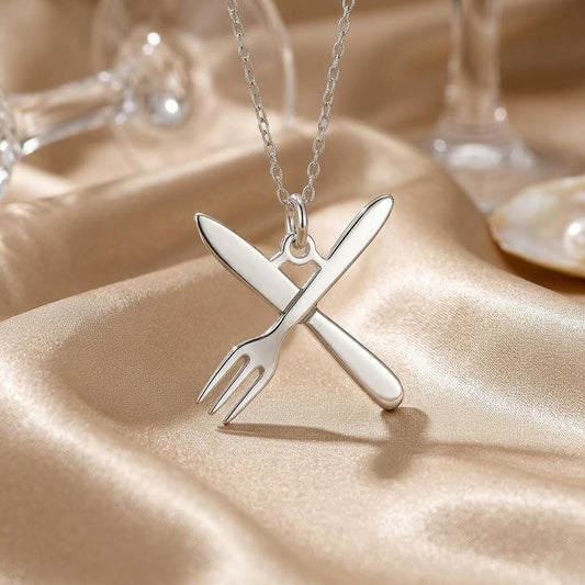 Close-up of the crossed fork and knife pendant on champagne satin