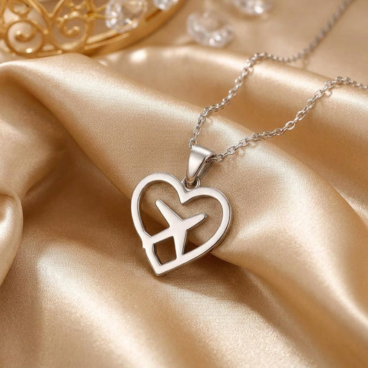 Close-up of the Heart Airplane Necklace on champagne-colored satin