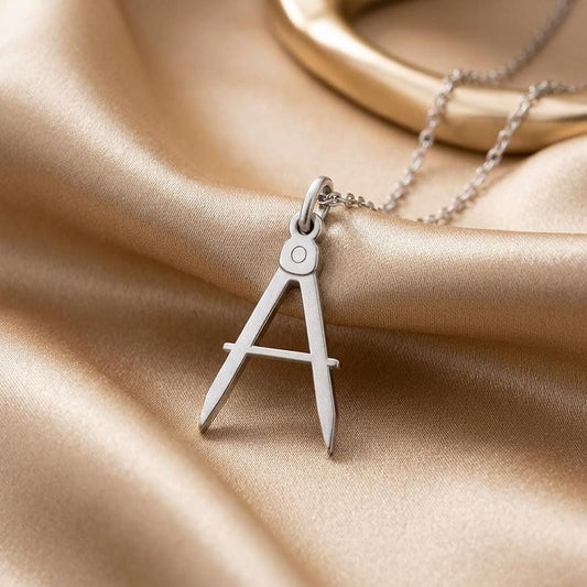 Architect Compass Necklace pendant on champagne satin showing the round pivot and central-tab crossbar