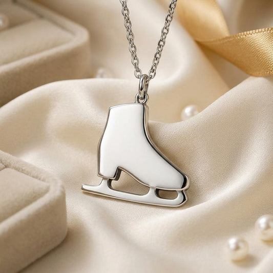 Close-up of polished figure skate pendant necklace on cream satin with a jewelry box and pearl accents