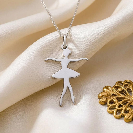 Close-up of the polished ballet dancer pendant with crossed downward-pointing feet on cream satin