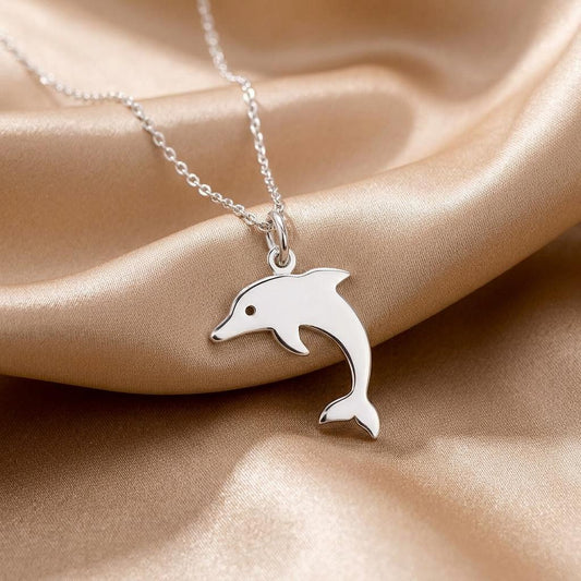 Close-up of a solid-silhouette dolphin pendant necklace on champagne-colored satin