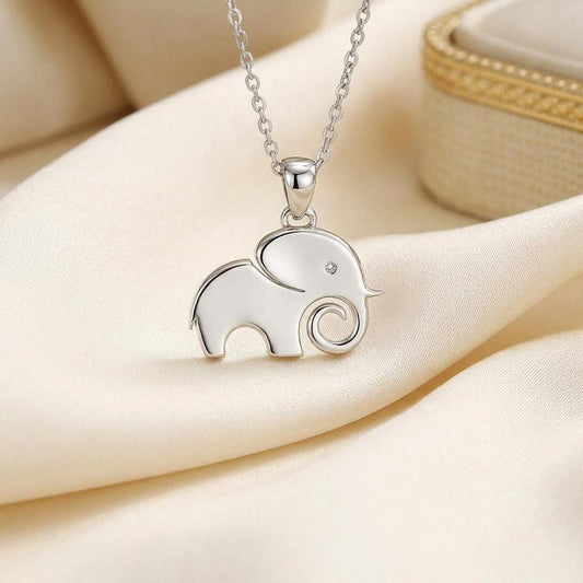 Close-up of a polished solid elephant pendant with circular eye detail and curled trunk on cream satin